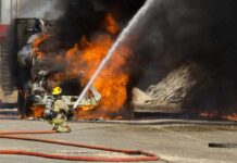Grease-Fueled Inferno Stuns Brooklyn Firefighter spraying water on a vehicle engulfed in flames