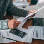 Grid Spending Surge Pounds California Families Person reviewing bills with calculator at cluttered desk