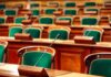 $9.5B Vanish – Millions Paid Not To Work Empty legislative chamber with green upholstered chairs and wooden desks