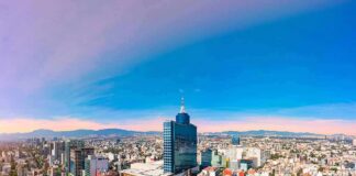 City skyline with tall blue-glass tower at center under clear sky