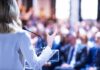 Communism Creep? Defector Sounds Alarm Speaker at podium addressing a blurred audience