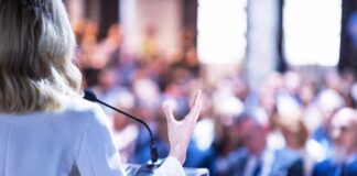 Speaker at podium addressing a blurred audience