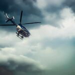 Police helicopter flying under dark storm clouds
