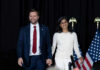 Near-Fall Fury: Protocol Or Failure? Two people holding hands on stage with U.S. flags behind them