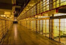 Prison cell block corridor with barred cells and upper walkways