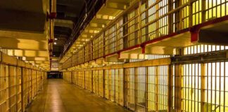 Prison cell block corridor with barred cells and upper walkways