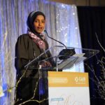 Ilhan Omar speaking at a podium on a decorated stage