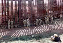 Border Crisis Triggers Trade Shock Soldiers install concertina wire along a tall border fence