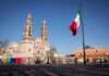 Washington Freezes Assets – Mexico Fires Back Mexican flag waving in a plaza with a historic cathedral