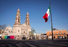 Washington Freezes Assets – Mexico Fires Back Mexican flag waving in a plaza with a historic cathedral