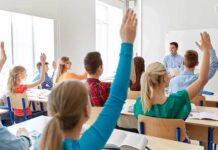 Union War Erupts Over Classroom Rules Students raise hands in a classroom with a teacher at the front