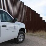Roads, Sensors Paused After Court Shock Border patrol SUV parked beside tall steel border fence