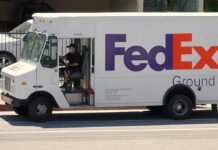 FedEx Ground delivery truck with driver wearing a mask