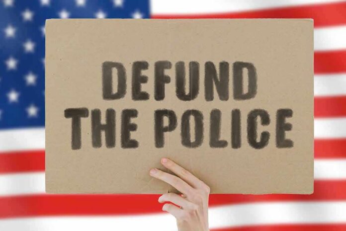 shutterstock_1753514282 Hand holding protest sign against blurred American flag