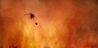 Helicopter fights massive wildfire over burning forest