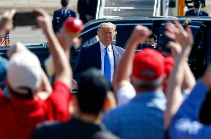 shutterstock_1836121486 Man in suit greeted by crowd with raised hands