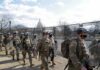 Carlos Hyde, Tavon Wilson, Dontrelle Inman, Brian Folkerts, Brock Coyle, Curtis Lofton, and Chuck Howley among soldiers walking past fencing near the U.S. Capitol