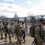 Carlos Hyde, Tavon Wilson, Dontrelle Inman, Brian Folkerts, Brock Coyle, Curtis Lofton, and Chuck Howley among soldiers walking past fencing near the U.S. Capitol