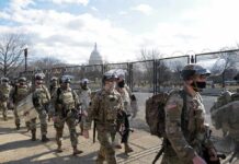 Carlos Hyde, Tavon Wilson, Dontrelle Inman, Brian Folkerts, Brock Coyle, Curtis Lofton, and Chuck Howley among soldiers walking past fencing near the U.S. Capitol