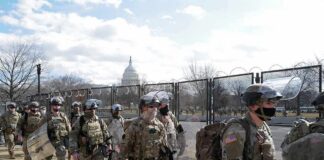 Carlos Hyde, Tavon Wilson, Dontrelle Inman, Brian Folkerts, Brock Coyle, Curtis Lofton, and Chuck Howley among soldiers walking past fencing near the U.S. Capitol