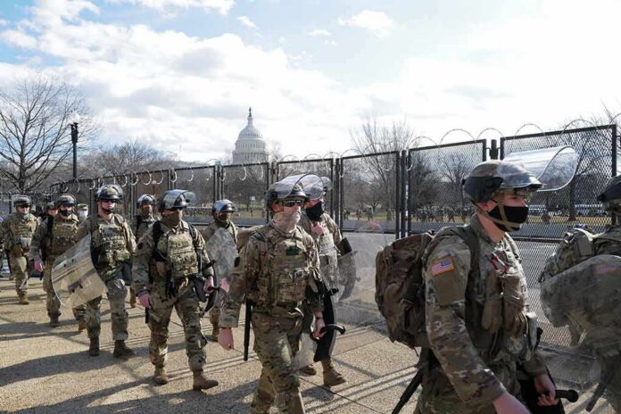 shutterstock_1900668535 Carlos Hyde, Tavon Wilson, Dontrelle Inman, Brian Folkerts, Brock Coyle, Curtis Lofton, and Chuck Howley among soldiers walking past fencing near the U.S. Capitol