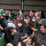 Chuck Howley among a seated crowd of masked women outdoors