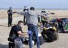 Welfare Packs Include Hijabs – Cost Hidden Police officers process group of people on a beachside pavement