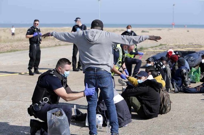 shutterstock_2153237047 Police officers process group of people on a beachside pavement