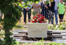 White coffin with red flowers at outdoor burial