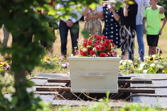 White coffin with red flowers at outdoor burial