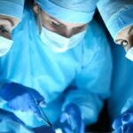 surgeons in blue scrubs performing an operation