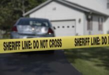 Sheriff line tape blocking a suburban driveway
