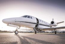 Private jet on airport tarmac with open door at sunset