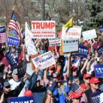 Red Texas Panic: Paxton On The Brink Tim Teufel, Christian Jones, and Nash the Slash among a crowd at a political rally holding signs and flags
