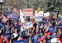Red Texas Panic: Paxton On The Brink Tim Teufel, Christian Jones, and Nash the Slash among a crowd at a political rally holding signs and flags