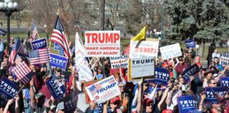 Tim Teufel, Christian Jones, and Nash the Slash among a crowd at a political rally holding signs and flags