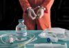 Pentobarbital Drama: Texas Pushes Through Handcuffed person in orange jumpsuit behind medical vials and IV equipment