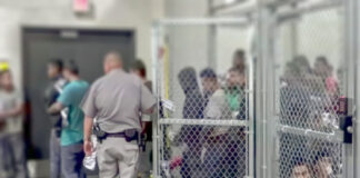 People detained behind fencing in a detention center.
