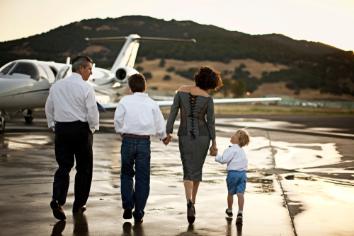 Family walking towards a private jet on a runway.