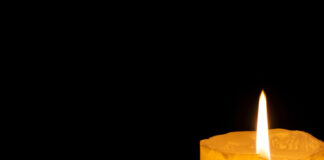 Lit candle in darkness.