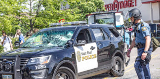 Damaged Saint Paul Police car with officer nearby.