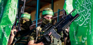 Two armed masked soldiers with green flags.