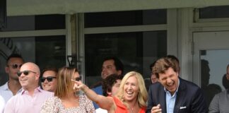 Group of people standing and smiling at golf event.