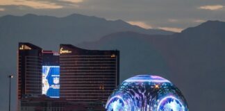 Las Vegas Sphere illuminated near hotels at dusk.