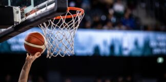 A basketball player reaching for the hoop with a ball