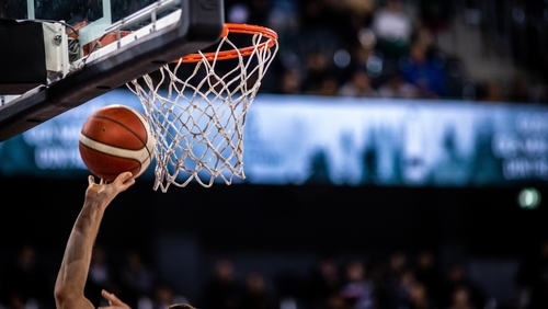 A basketball player reaching for the hoop with a ball