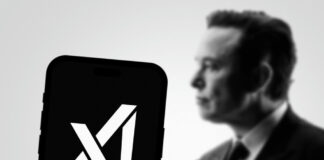 Phone displaying X logo, blurred background person.