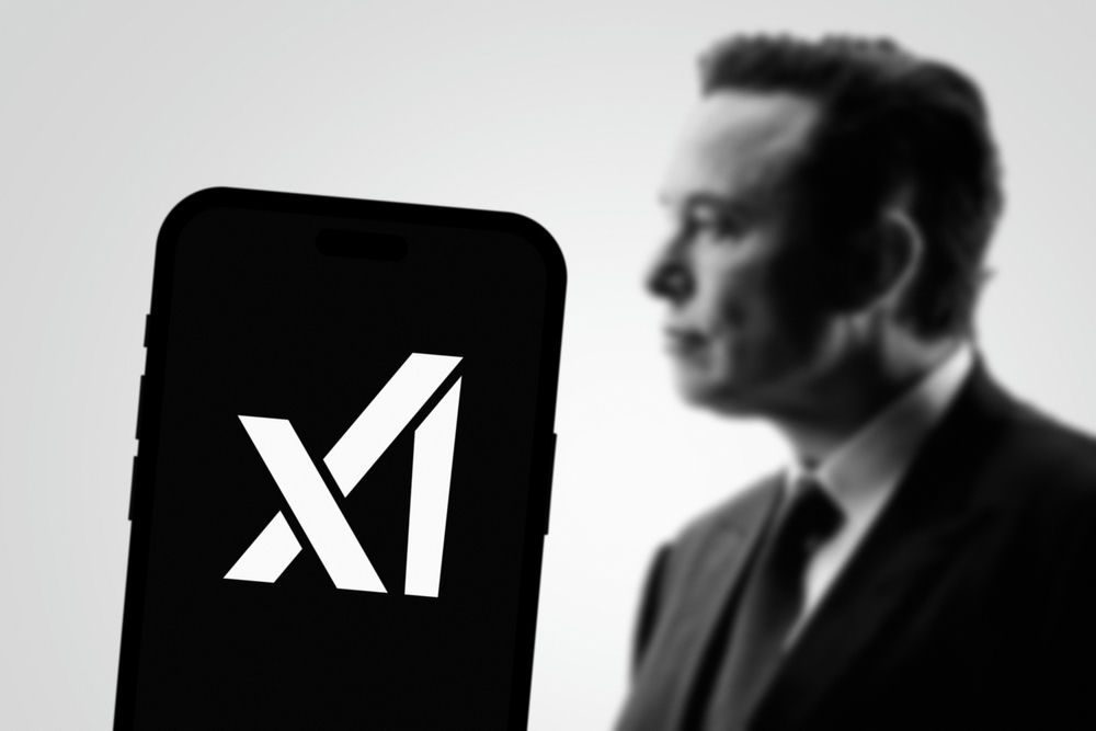 Phone displaying X logo, blurred background person.