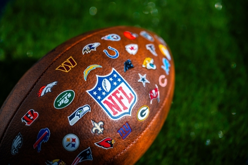Close-up of an NFL football featuring various team logos on its surface