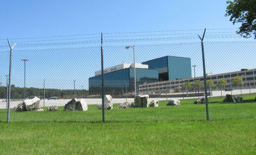 Chain-link fence in front of a large modern office complex